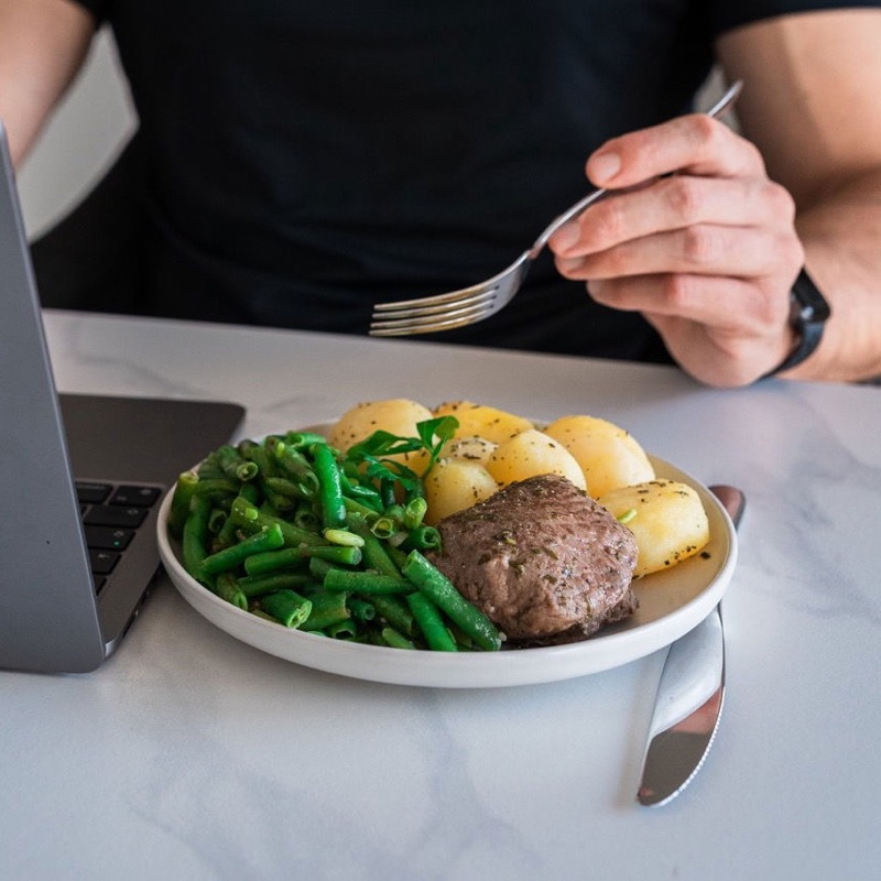 Proteinreiches Fertiggericht von prepmymeal neben einem Laptop